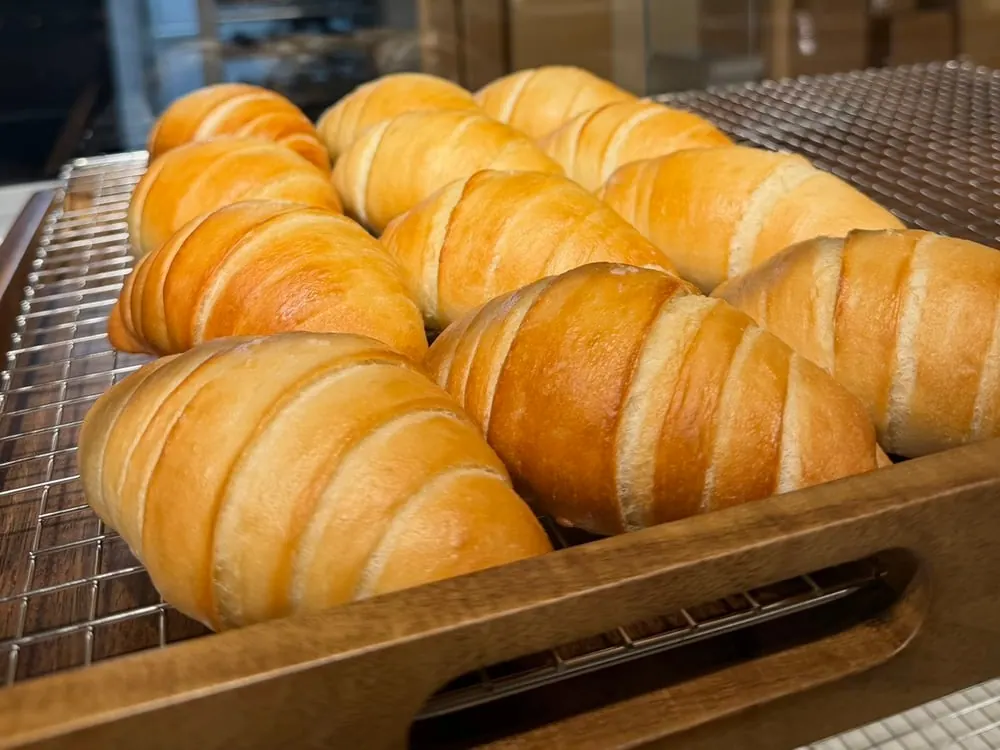 Freshly baked salt bread (shio pan) on a wooden tray at Sora Bake & Tea Room